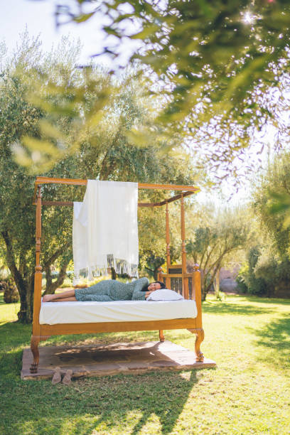 istock Young woman relaxes on a bed in a garden setting 1358258484
