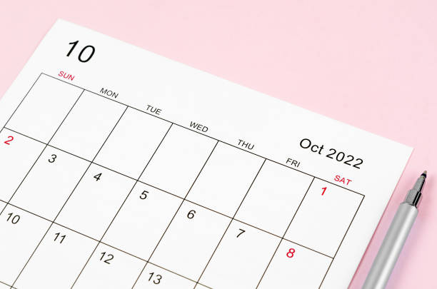 istock October 2022 calendar sheet with pen on pink background. 1358259347
