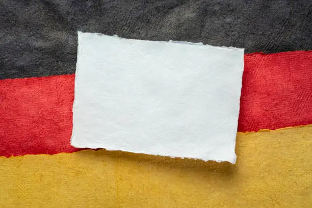 blank sheet of white paper against abstract in colors of Germany national flag - black, red and gold, October is German American Heritage Month