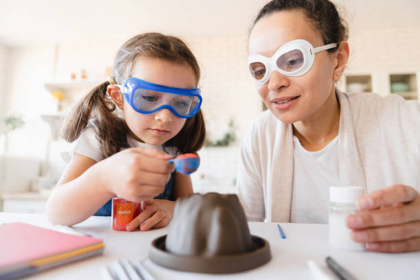 esperimento scientifico domestico del vulcano con bicarbonato di sodio. eruzione per kid. figlia con la madre che fa esperimento chimico domestico con la sostanza insieme - home schooling foto e immagini stock