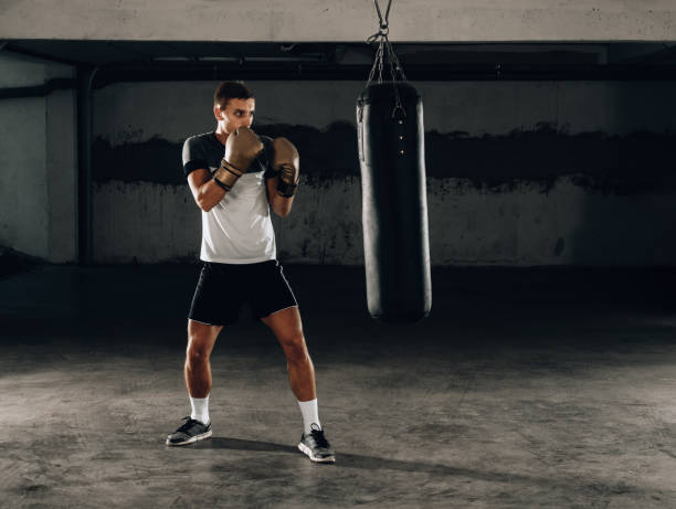 istock Strength male boxer training with punching bag. Boxing exercise 1358267066
