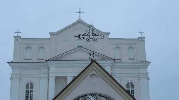 The Church of saints Cosmas and Damian in Ostrovets Grodno region with branch of tree on grey sky background. Worhsip and historical heritage concepts.
