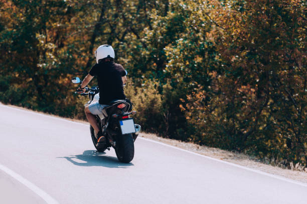 istock Back view of motorcycle driver driving in beautiful sunset 1358268338