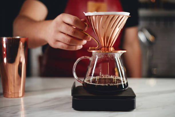 Barista making a drip coffee, pouring hot water from kettle over a coffee powder