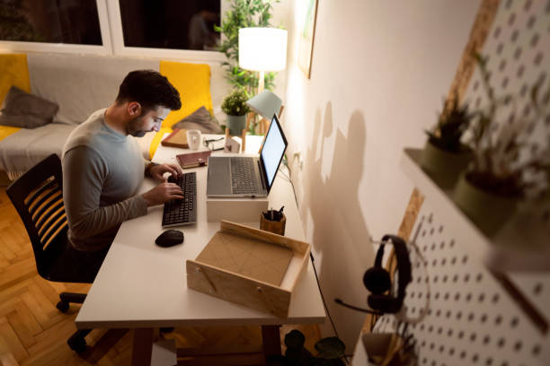 istock Late at night from home office, dedicated man working on laptop 1358273490