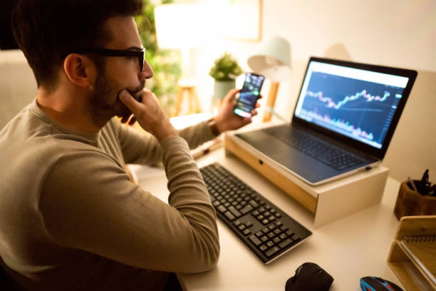 Caucasian man investing or trading in Bitcoin or other cryptocurrencies Caucasian man working with blockchain technologies, analyzing crypto graph on laptop screen, late at night from his home office.  Depicts TradingView financial market chart. financial occupation stock pictures, royalty-free photos & images