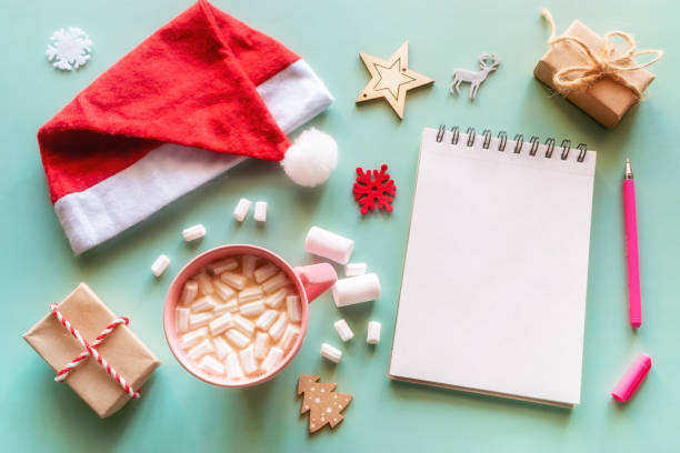 istock blank notepad with place for text, santa claus hat, coffee mug with marshmallows and christmas decorations concept wish list, shopping list 1358273893