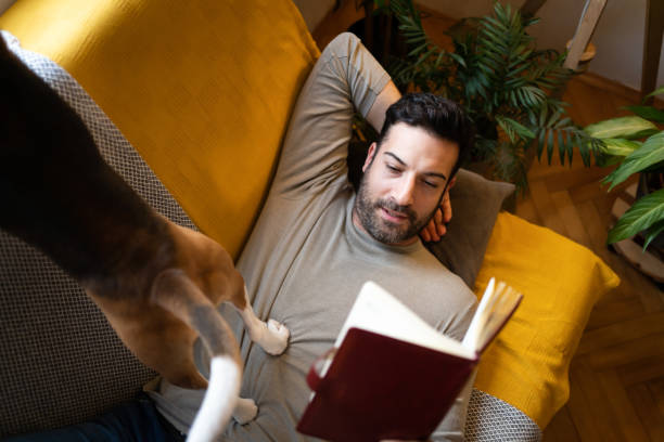 istock Serene mid-adult man lying on the sofa and reading book 1358274457