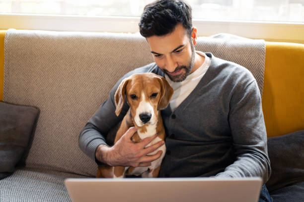 istock Cheerful man embracing his dog during video call on laptop 1358274487