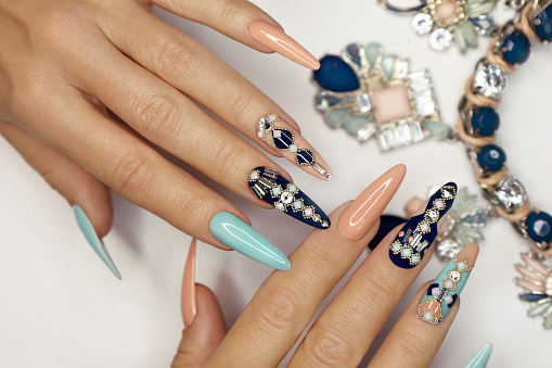 Stock photo showing close-up view of a woman displaying her engagement ring and manicured painted nails design.