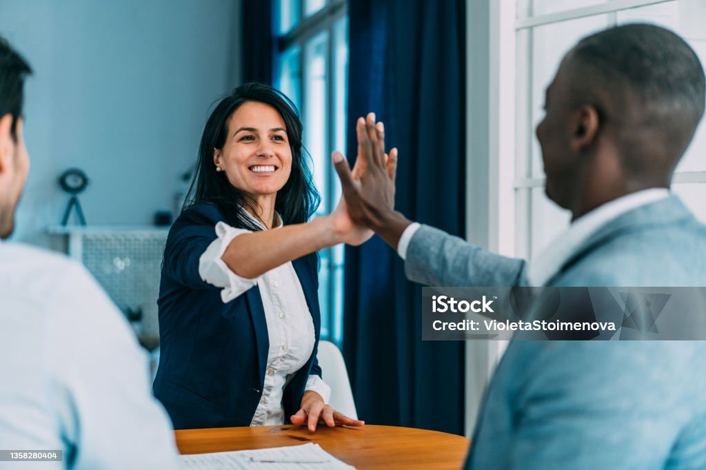 Motivating the team. Shot of business persons doing high-five greeting in the office. Successful business people stacking hands in modern office. Community Stock Photo