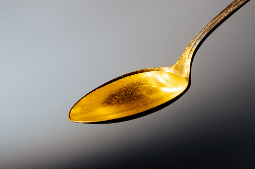 Cod liver oil liquid on a metal spoon.