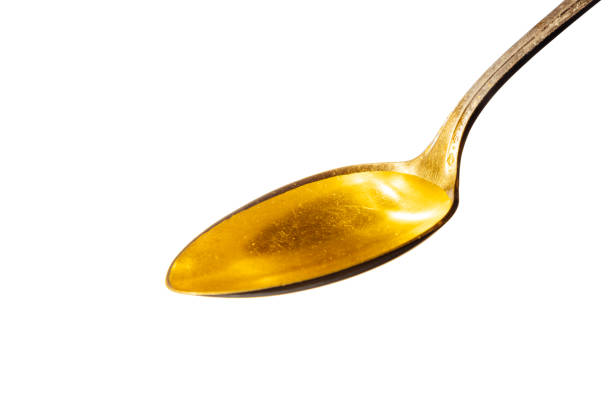 Cod liver oil liquid Cod liver oil liquid on a metal spoon. animal liver stock pictures, royalty-free photos & images