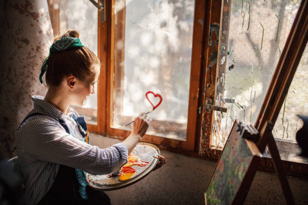 Portrait with copy space of a female artist painting in a rustic room