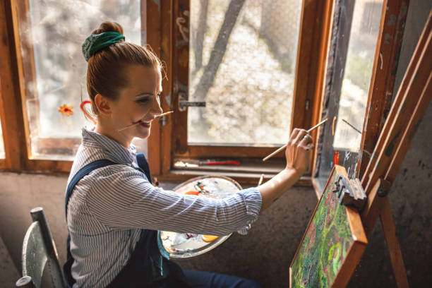 istock Beautiful artist drawing on windows in rustic room 1358283837