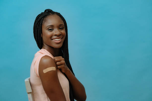 istock Vaccinated attractive young woman smiling with plaster on hand right after getting covid-19 vaccine shot 1358285123