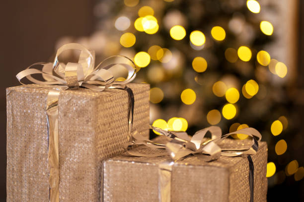 istock Boxes with gifts in silver wrapping on a background of christmas lights 1358285708