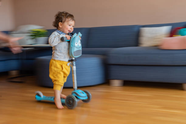 istock Boy riding scooter at home 1358285914