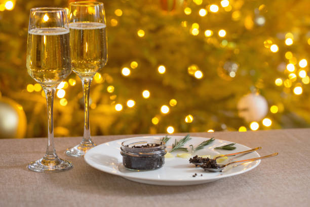 背景のクリスマスツリーに黒いキャビアとシャンパンのグラス - champagne celebration glass black ストックフォトと画像