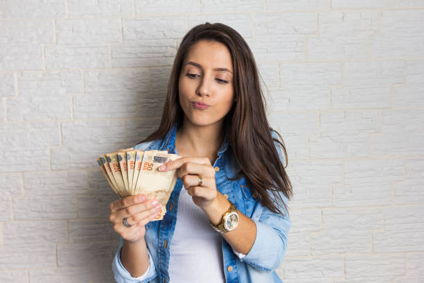 Girl holding a large amount of cash, a lot of money from Brazil. Lovely beautiful girl is holding a large amount of cash, a lot of money from Brazil. Business, income, loan, pay, buy, wealth concept. brazilian currency photos stock pictures, royalty-free photos & images