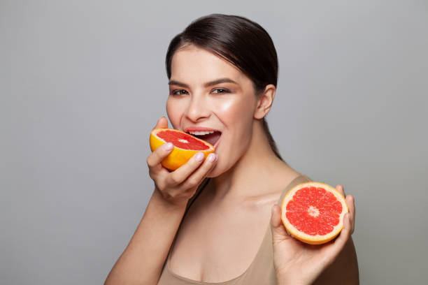 istock Smiling woman holding two grapefruits in hands 1358288359