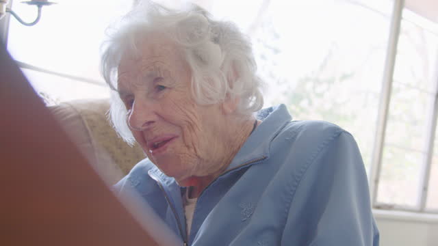 Handheld Shot of a Cheerful Elderly Woman's Face While She is Playing a Piano Keyboard at Home