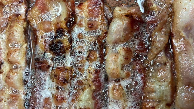 Slices of Hot Sizzling Bacon Cooking