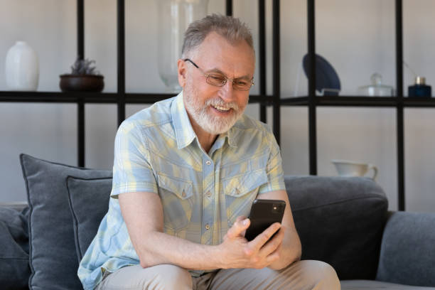 istock Happy mature 60s smartphone user reading text message on gadget 1358295190