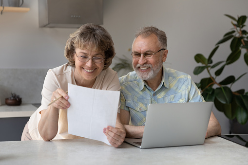 Happy satisfied mature couple of retirees reading paper document