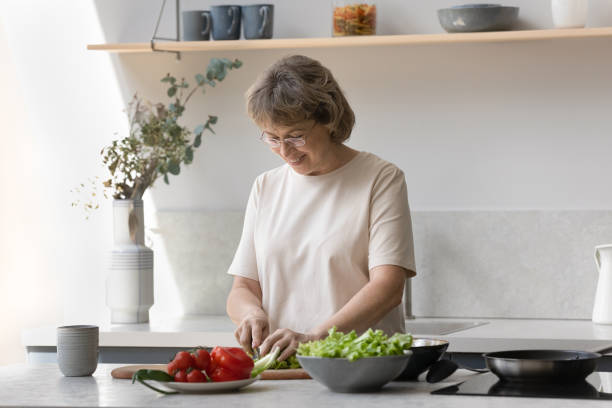 istock Happy older lady cutting vegetables, natural ingredients for salad 1358295216