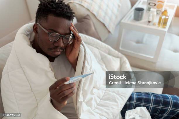 Ill Man Covered With Blanket Holding Thermometer Stock Photo - Download Image Now - Fever, Illness, Males