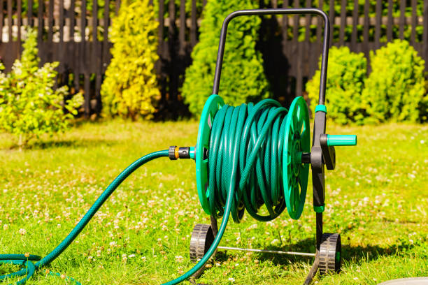 istock Garden hose for watering plants in garden 1358296433