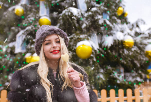 istock Lovely lady with chocolate candy walking near the New year tree 1358296824