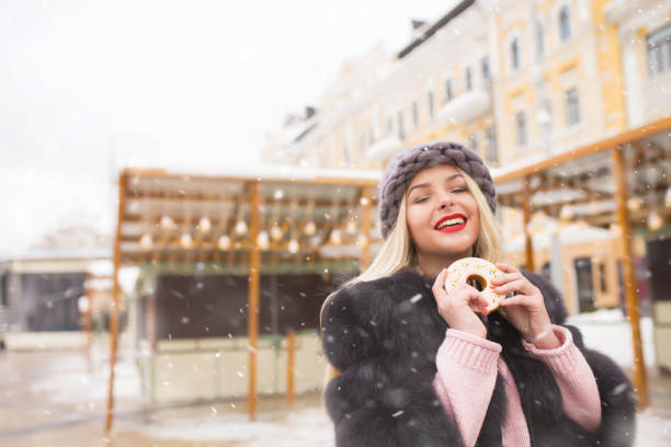 istock Merry lady biting gingerbread at the holiday fair 1358297632