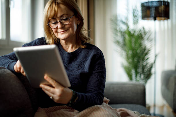istock Smiling mature woman using digital tablet at home 1358297854