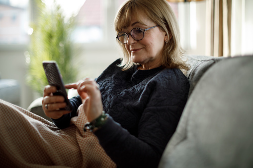 Smiling mature woman using mobile phone at home