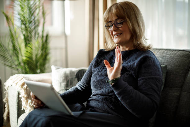 istock Smiling mature woman using digital tablet for video call at home 1358298115