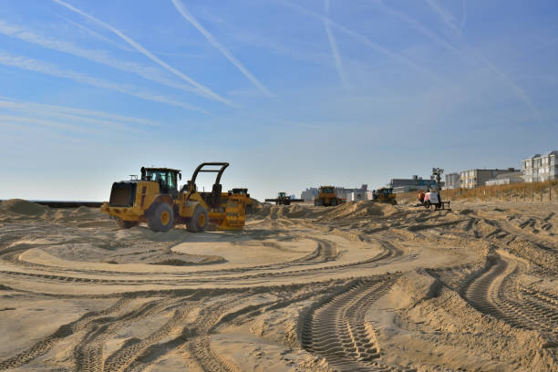 Beach restoration equipment and materials on the Ocean City, MD beach with beach condos in the background on a bright December morning with vapor trails in a blue sky