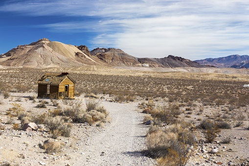 Isolated Ruins of Old Wooden Log Cabin with Scenic Desert Landscape and Distant Mountain Peaks at Historical Rhyolite Ghost Town, near Death Valley National Park Nevada USA