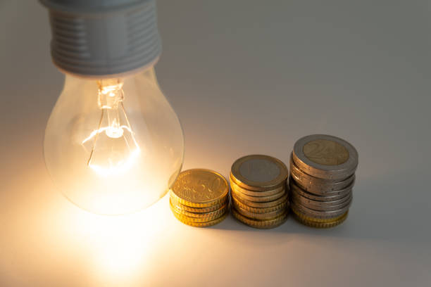 istock Light bulb on, with coins, banknotes and energy bills next to it. 1358301124