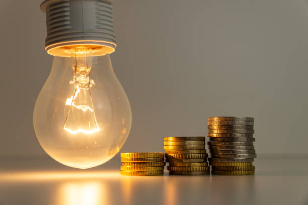 istock Light bulb on, with coins, banknotes and energy bills next to it. 1358301126