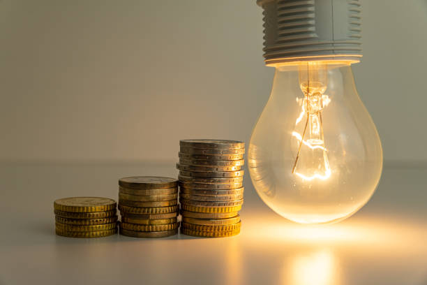 istock Light bulb on, with coins, banknotes and energy bills next to it. 1358301132