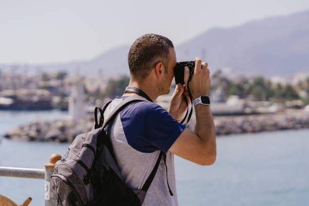 istock Tourist man with backpack taking photos while traveling 1358301207