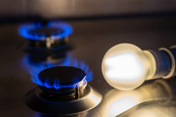 ampoule allumée et cuisinière à gaz allumée. - gas prices energy crisis environment finance photos et images de collection