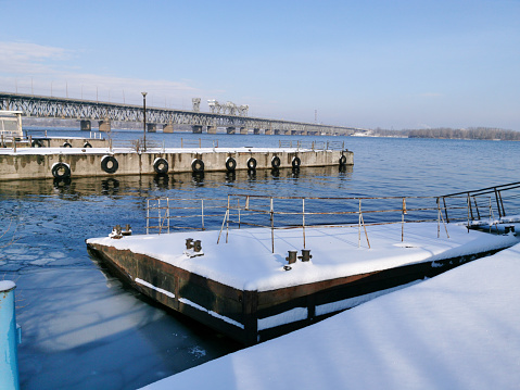 Winter view of the abandoned river piers on the Dnieper. Rusty bollards in the snow. The piers are covered with snow.