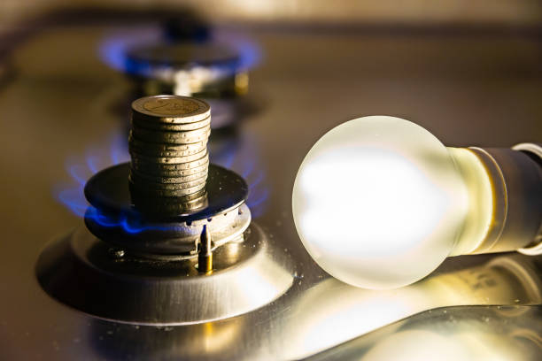 Light bulb on and gas cooker on. Light bulb on next to lit gas cooker. Energy and gas costs, cost increases. energy crisis photos stock pictures, royalty-free photos & images