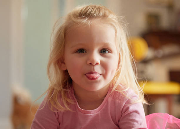 foto de una adorable niña sacando la lengua - little girls small blond hair child fotografías e imágenes de stock