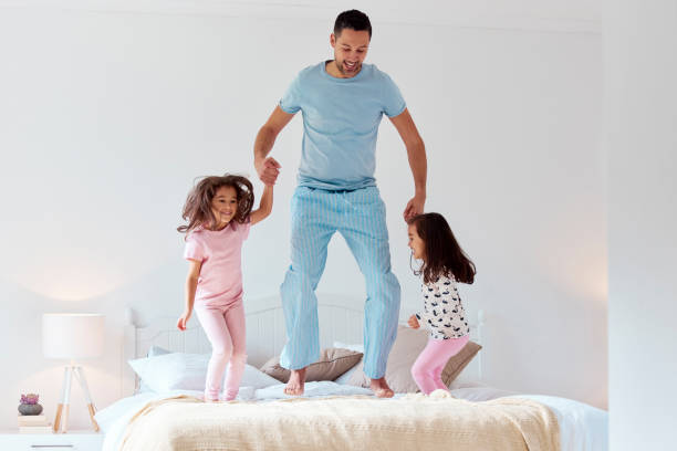 istock Shot of a man jumping on a bed with his two daughters 1358307347