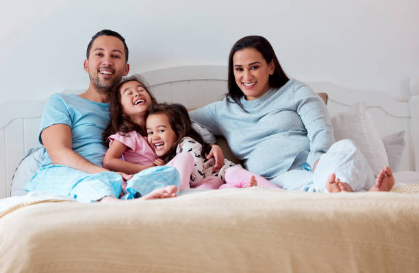 istock Shot of a couple lying on bed with their two daughters 1358307366