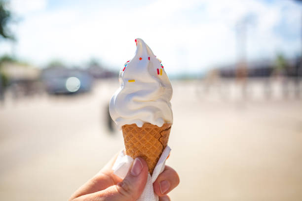 Girl'S Hand Holding Ice Cream In Waffle Cone Decorated With Pills a hot day outside stock photo